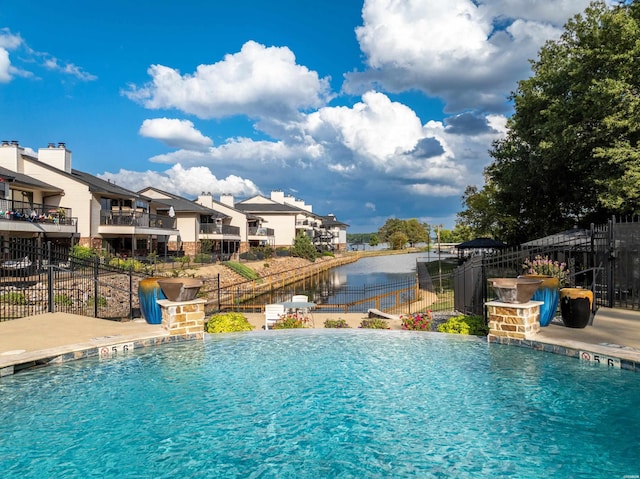 pool featuring a residential view, a water view, and fence