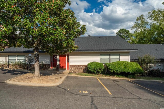 single story home featuring uncovered parking, brick siding, and a shingled roof