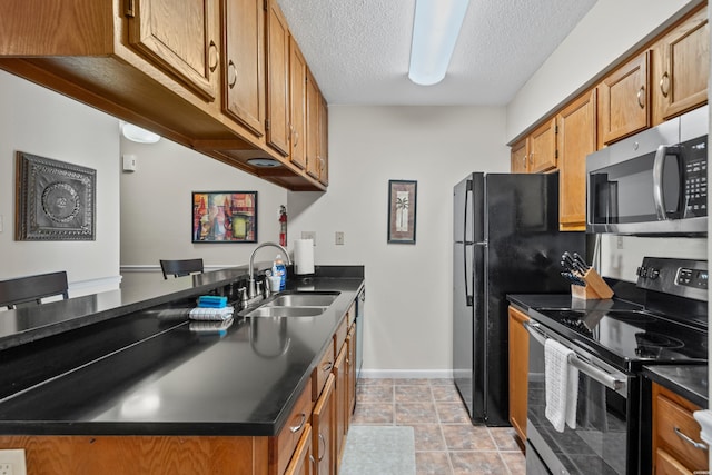 kitchen with dark countertops, brown cabinets, stainless steel appliances, and a sink