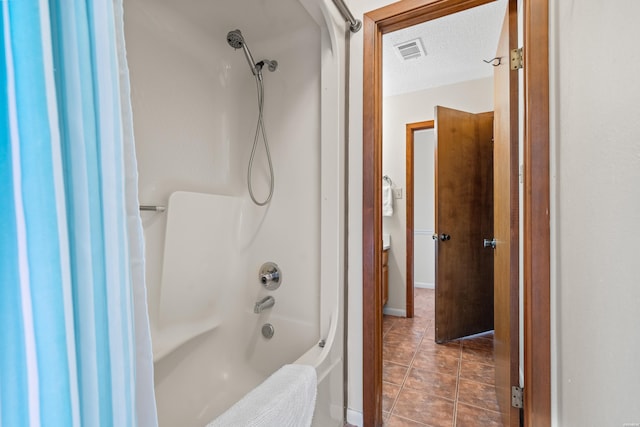 bathroom with tile patterned flooring, visible vents, a textured ceiling, and shower / bathing tub combination