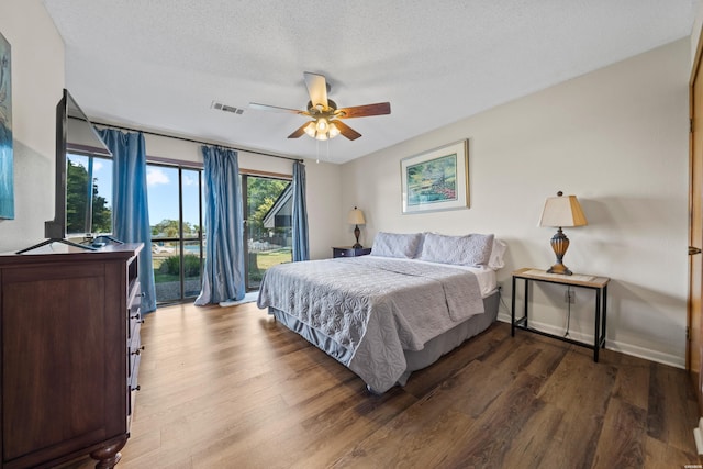 bedroom with baseboards, visible vents, wood finished floors, access to outside, and a textured ceiling