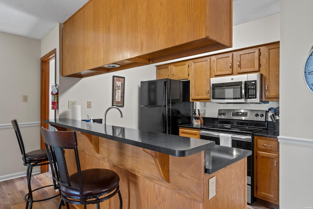 kitchen featuring appliances with stainless steel finishes, dark countertops, and brown cabinetry