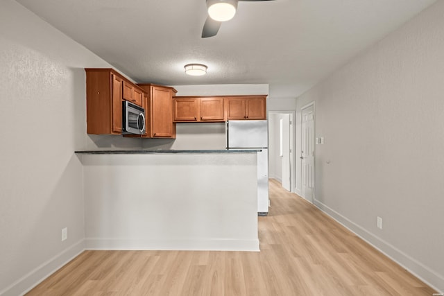 183 River Mill Ct Unit B-1, Hot Springs, AR 71913 - kitchen featuring stainless steel microwave, freestanding refrigerator, light wood-style flooring, a peninsula, and brown cabinets