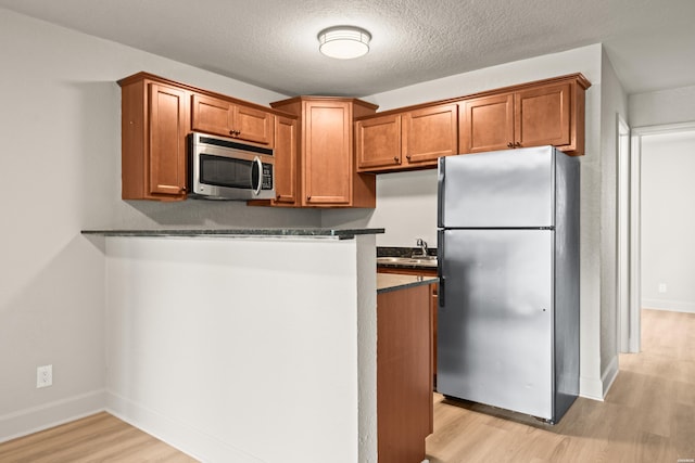 183 River Mill Ct Unit B-1, Hot Springs, AR 71913 - kitchen featuring stainless steel appliances, light wood-style floors, dark countertops, brown cabinetry, and a peninsula