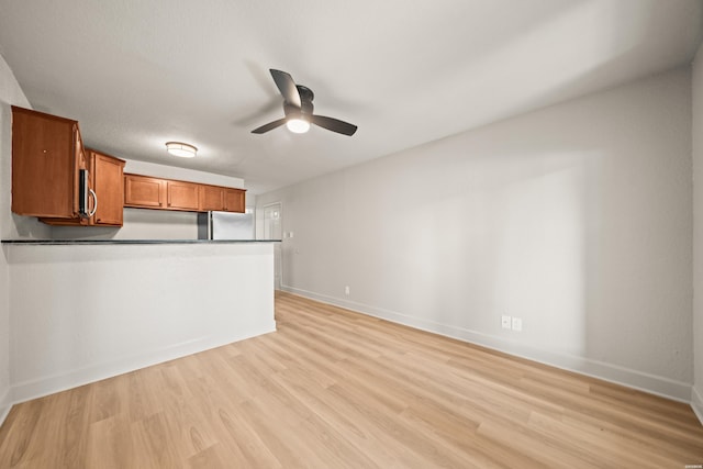 183 River Mill Ct Unit B-1, Hot Springs, AR 71913 - kitchen with brown cabinets, stainless steel appliances, a ceiling fan, dark countertops, and light wood-style flooring