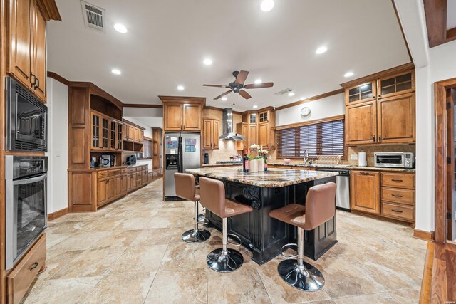 kitchen featuring a breakfast bar area, appliances with stainless steel finishes, glass insert cabinets, a kitchen island, and wall chimney exhaust hood