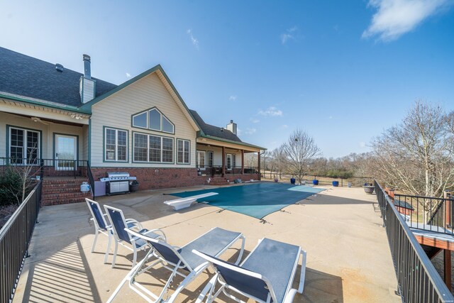 view of swimming pool featuring a fenced in pool, a patio area, area for grilling, and a diving board