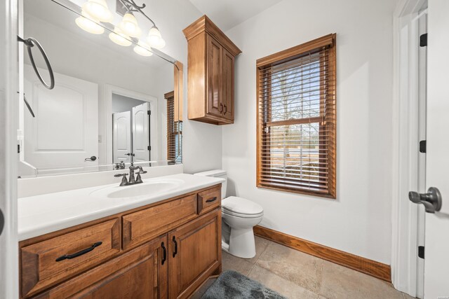 bathroom with toilet, vanity, and baseboards