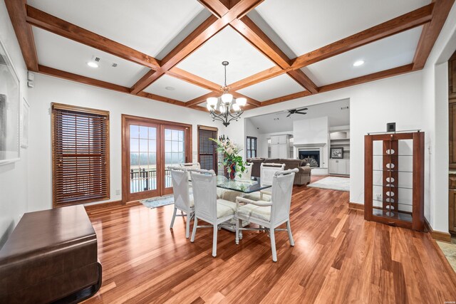 dining space with light wood-style floors, a fireplace, coffered ceiling, and beam ceiling