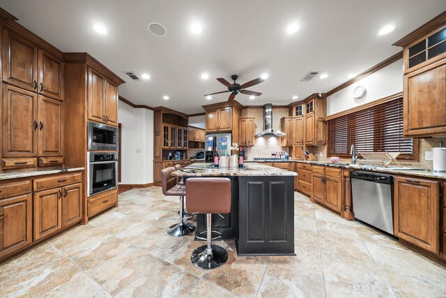 kitchen with stainless steel appliances, a center island, wall chimney exhaust hood, and light stone countertops