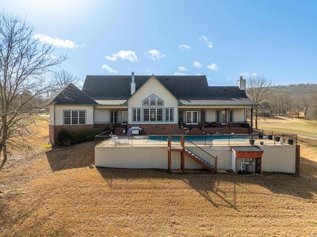 back of property featuring a patio area, a covered pool, and a chimney