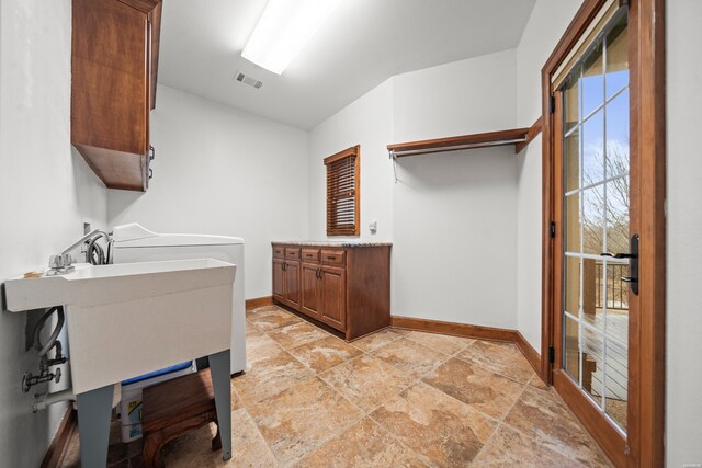 clothes washing area with cabinet space, baseboards, visible vents, and stone finish flooring