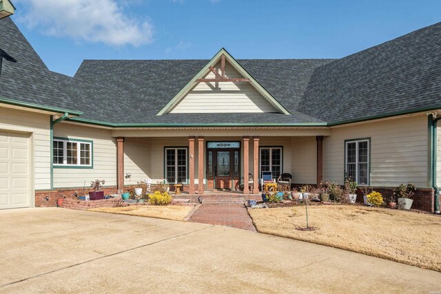 view of front of home featuring covered porch, roof with shingles, and brick siding