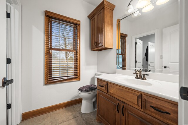 bathroom with toilet, vanity, baseboards, and tile patterned floors