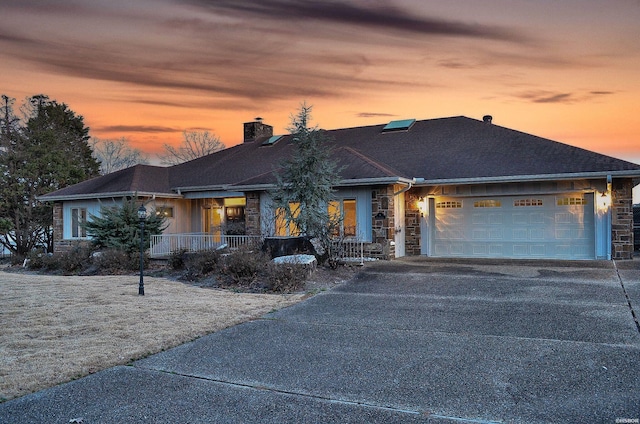 view of front of property with driveway, stone siding, an attached garage, and a chimney