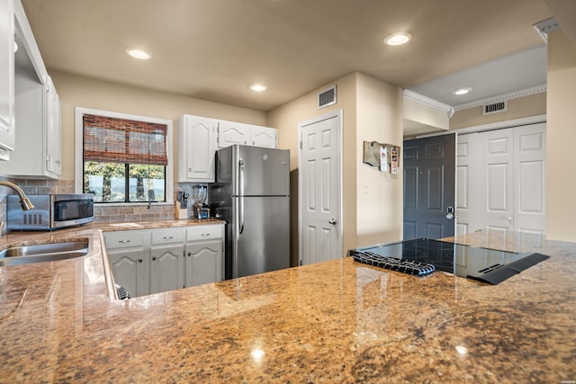 kitchen with stainless steel appliances, a sink, visible vents, and white cabinets