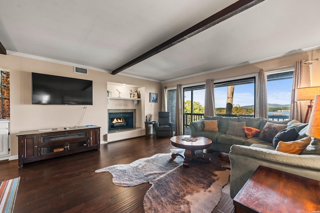 living area featuring dark wood-style flooring, beam ceiling, crown molding, visible vents, and a lit fireplace