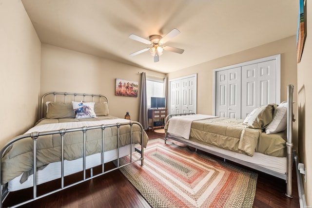 bedroom with ceiling fan, dark wood-type flooring, and multiple closets