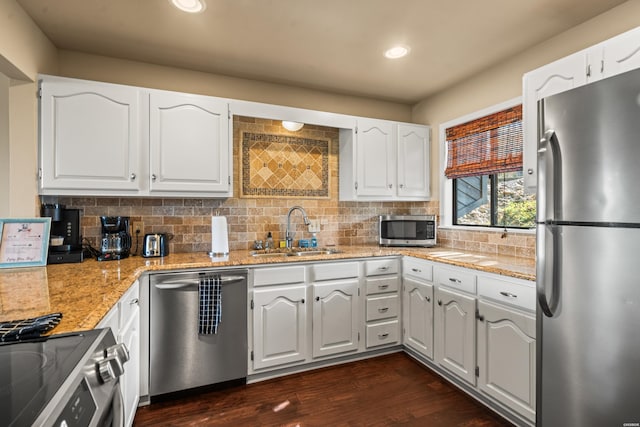 kitchen featuring appliances with stainless steel finishes, backsplash, a sink, and white cabinets