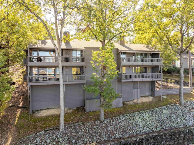 rear view of property with a balcony and a chimney