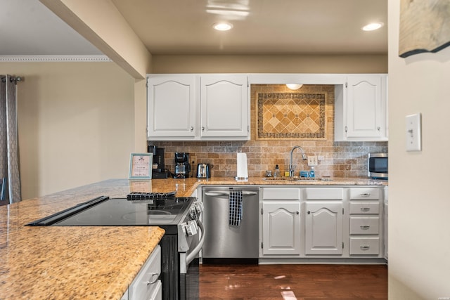 kitchen with stainless steel appliances, white cabinetry, a sink, and decorative backsplash