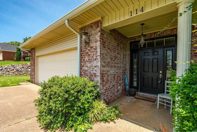 114 Cliffwood Loop, Hot Springs, AR 71913 - view of exterior entry featuring brick siding, concrete driveway, an attached garage, and board and batten siding