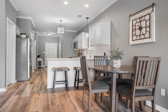 128 Kaleigh Ct Unit B, Hot Springs, AR 71913 - kitchen featuring appliances with stainless steel finishes, a peninsula, white cabinetry, light wood finished floors, and tasteful backsplash
