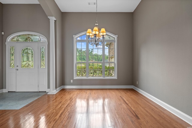 entryway with light wood-type flooring, baseboards, visible vents, and ornate columns