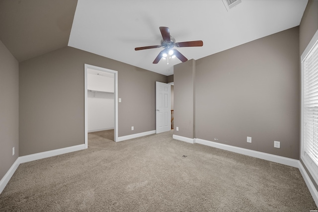 unfurnished bedroom featuring ceiling fan, light colored carpet, visible vents, baseboards, and a walk in closet
