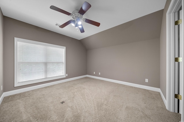 carpeted spare room featuring a ceiling fan, visible vents, vaulted ceiling, and baseboards