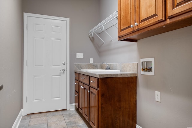 clothes washing area featuring washer hookup, cabinet space, a sink, and baseboards