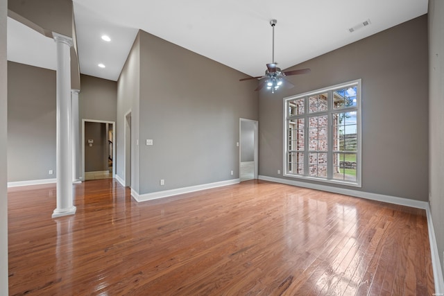 empty room featuring baseboards, wood finished floors, visible vents, and ornate columns
