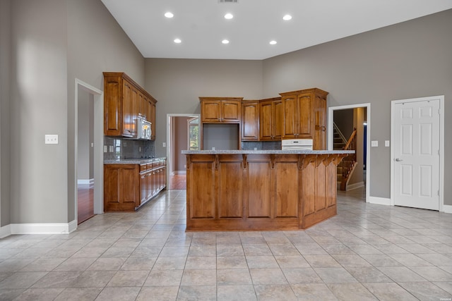 kitchen with brown cabinets, light tile patterned floors, tasteful backsplash, a kitchen island, and a kitchen breakfast bar