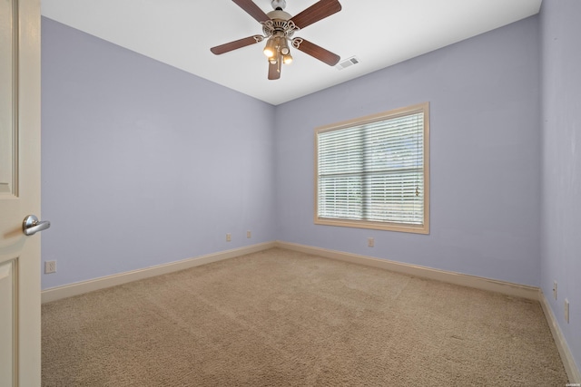 spare room featuring baseboards, visible vents, ceiling fan, and light colored carpet