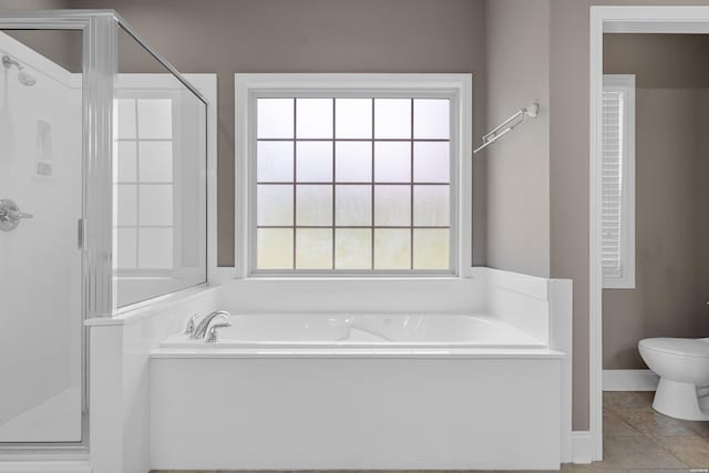 bathroom with a garden tub, a shower stall, toilet, and tile patterned floors