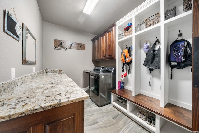 mudroom featuring a textured ceiling, washer and clothes dryer, and a sink