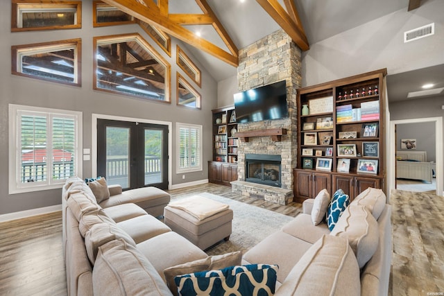 living room with high vaulted ceiling, a fireplace, wood finished floors, visible vents, and french doors