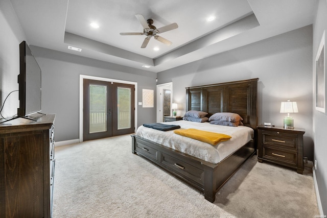 bedroom with baseboards, light colored carpet, access to exterior, a tray ceiling, and french doors