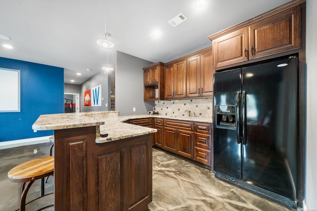 kitchen with a breakfast bar area, tasteful backsplash, visible vents, black fridge with ice dispenser, and a peninsula