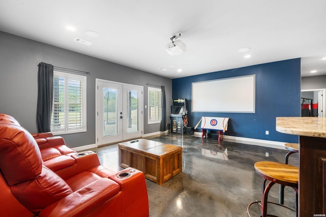 living area with finished concrete flooring, french doors, visible vents, and baseboards