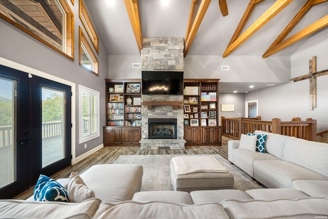 living area with high vaulted ceiling, a stone fireplace, wood finished floors, baseboards, and beam ceiling