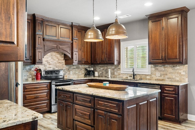 kitchen with stainless steel appliances, visible vents, a sink, and light wood finished floors