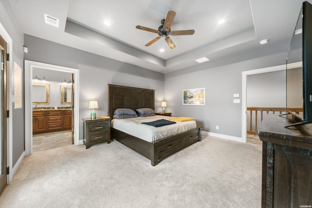 bedroom featuring light carpet, baseboards, visible vents, and a raised ceiling