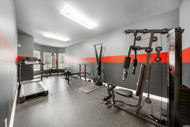 workout room with a textured ceiling and baseboards