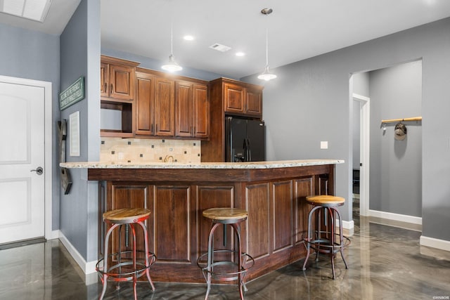 kitchen featuring tasteful backsplash, black fridge, visible vents, and baseboards