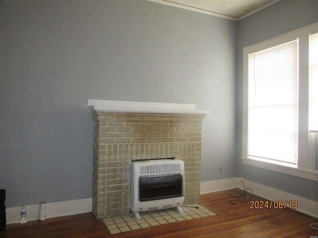 details featuring baseboards, ornamental molding, wood finished floors, heating unit, and a fireplace