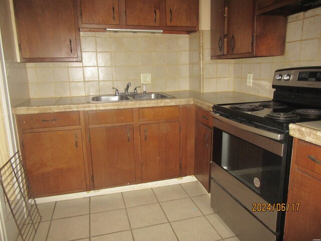 kitchen with light countertops, backsplash, stainless steel electric range, and a sink