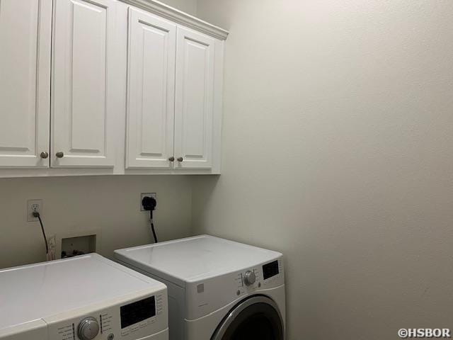 clothes washing area featuring cabinet space and washer and dryer