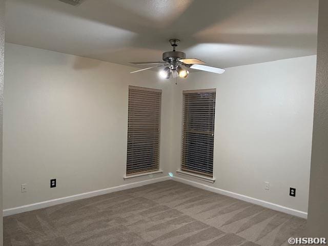 spare room featuring light colored carpet, ceiling fan, and baseboards