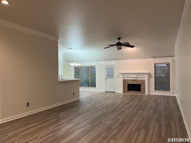 unfurnished living room with a fireplace, baseboards, wood finished floors, and ceiling fan with notable chandelier